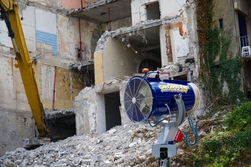Industrial demolition with dust control machine and debris. Outdoors in daylight.